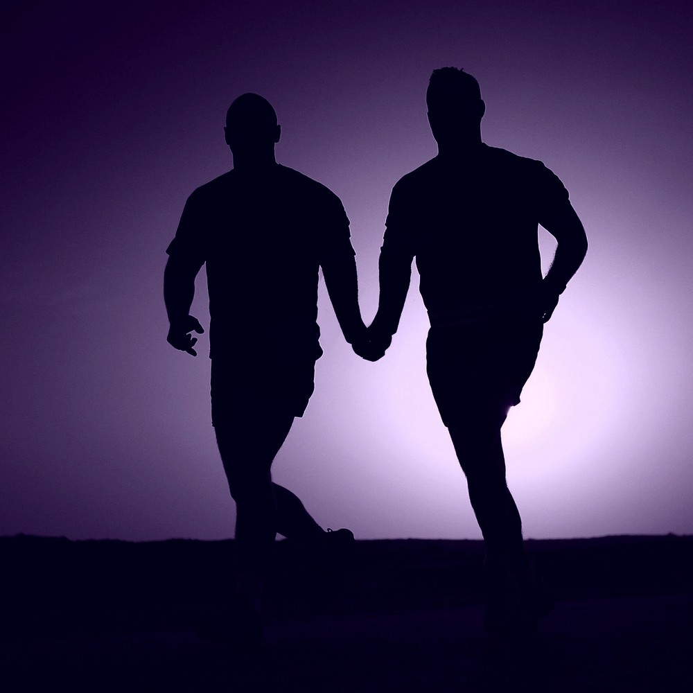 Two gay lovers running hand in hand in silhouette