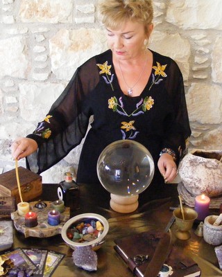 A woman dressed in black casting spells at ther altar