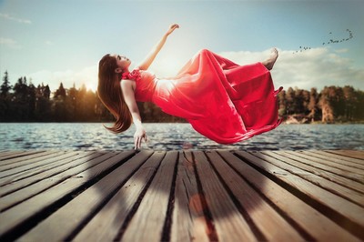 A woman in a red dress apparently floating above the ground.