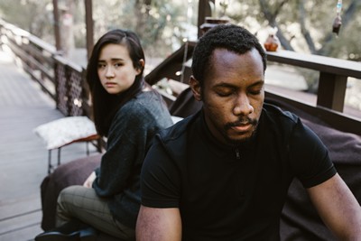 A man and a woman sitting on a bench that look upset.
