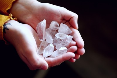 Hands gently holding a collection of clear quartz crystals, symbolizing energy, clarity, meditation and healing.