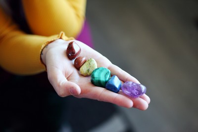 A hand holding a collection of colourful polished crystals, including amethyst, malachite, and others, symbolizing chakra alignment and energy balance. A hand holding a collection of colourful polished crystals, including amethyst, malachite, and others, symbolizing chakra alignment and energy balance.
