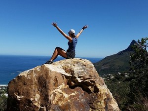 Woman celebrating with arms outstretched on top of a hill.