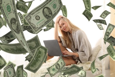 Money cascading onto woman at laptop