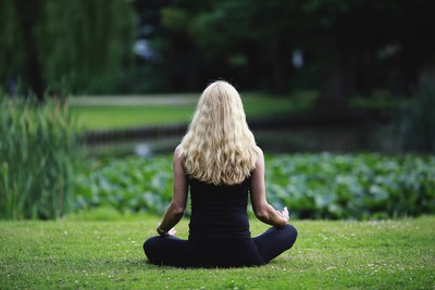 A Woman meditating in a field.