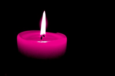 Lit pink candle on black background Lit pink candle on black background