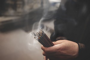 A person holding smouldering smudging sticks
