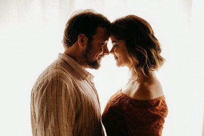 A man and a woman facing each other closely and smiling.