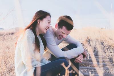 Couple laughing sat on the grass