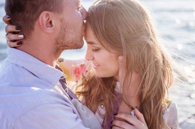 man kissing woman affectionately on the forehead.