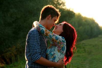 A man and a woman in a loving embrace outdoors.