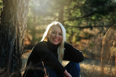 A person sitting against a tree in a forest.