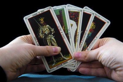 A pair of hands holding 4 Tarot Cards