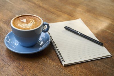 Cup of coffee, notebook and pen on a table