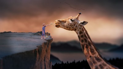 Dreamlike image of giraffe being fed by boy